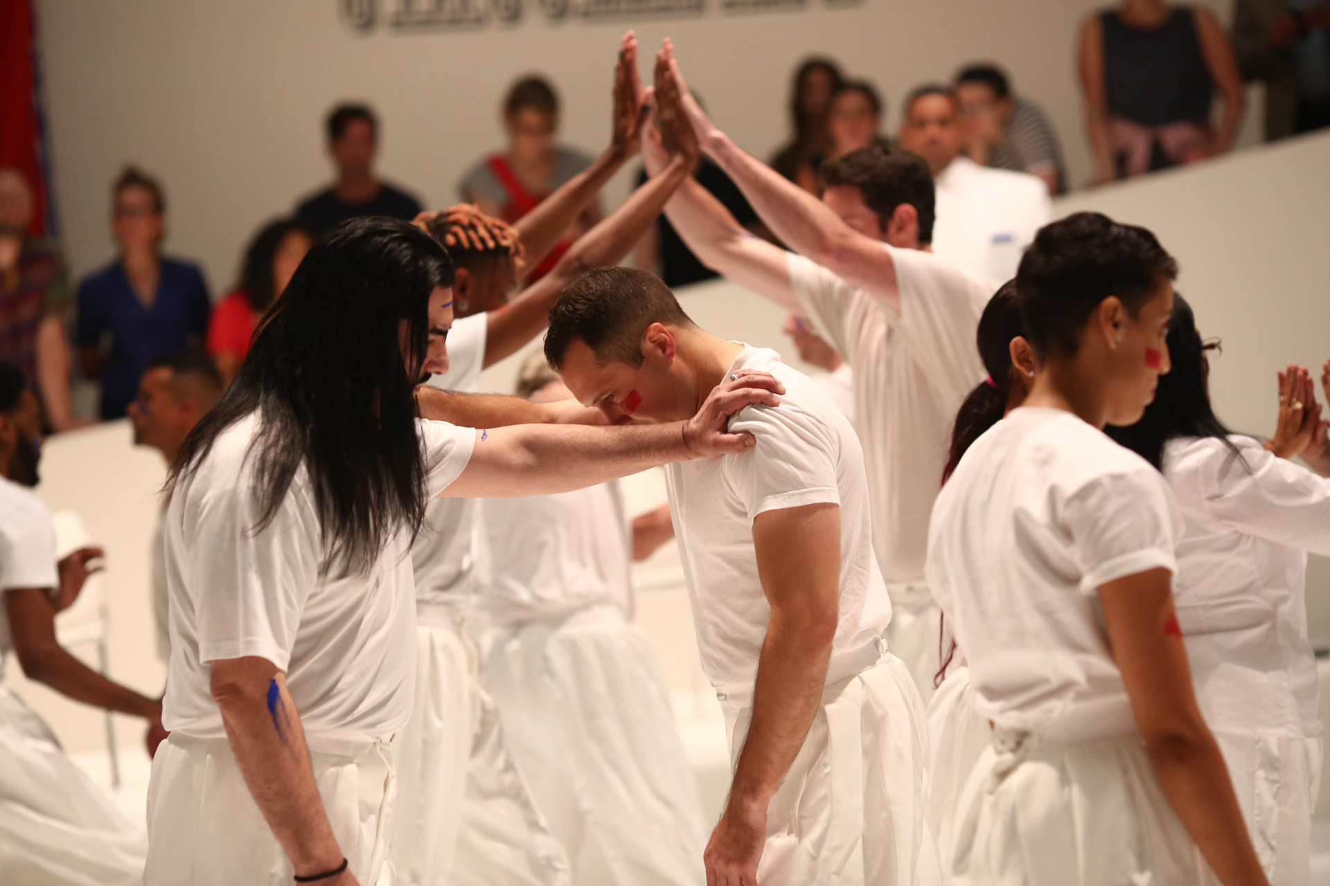 People in white joining hands and grasping each others' shoulders.
